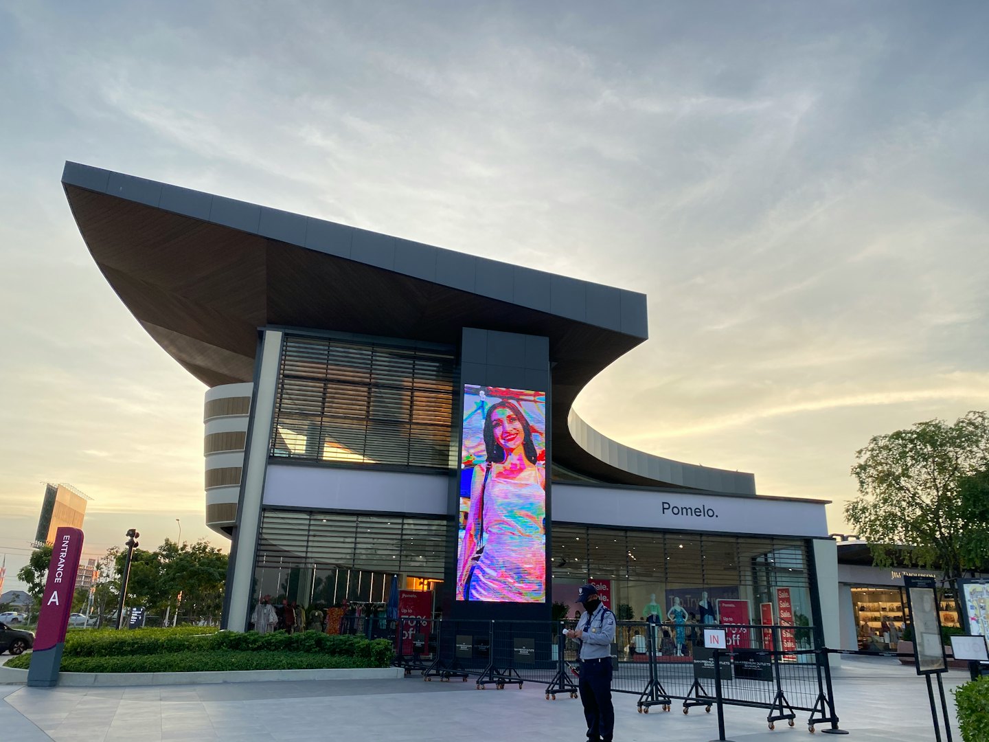 Security guard by entrance to modern building with digital ad.
